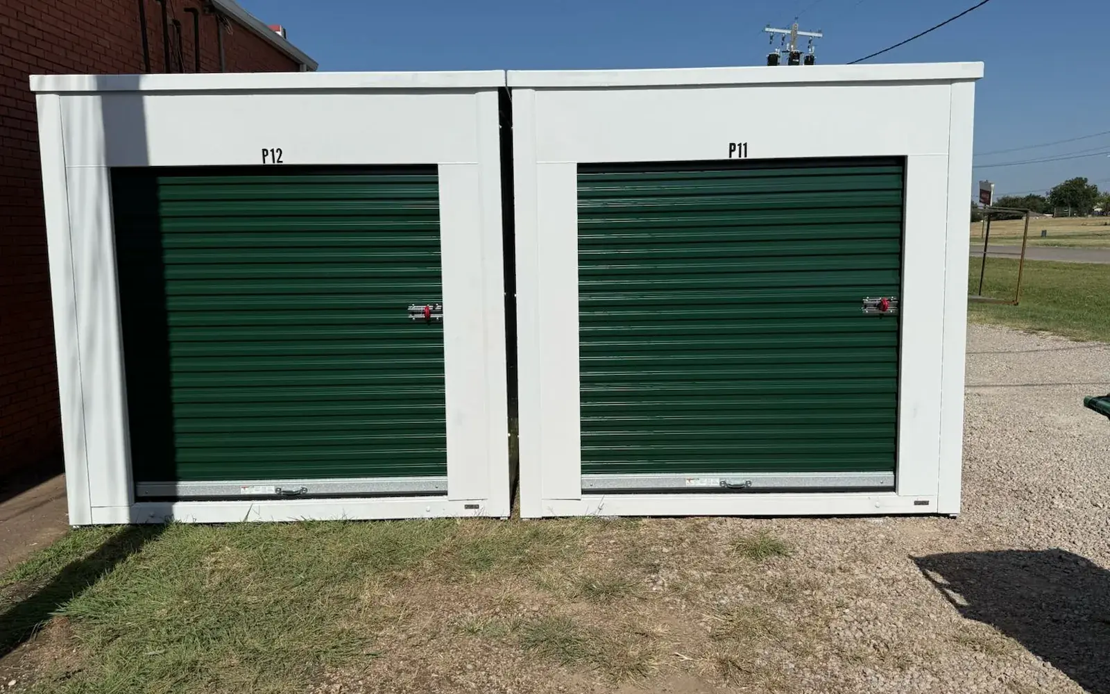 Outdoor storage containers with green roll up doors beside the building